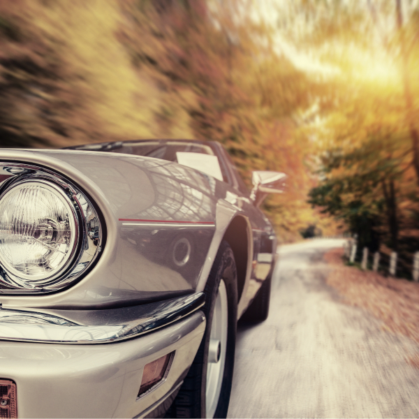 A classic car driving down a autumn coloured road sat on classic car tyres Classic Tyres UK