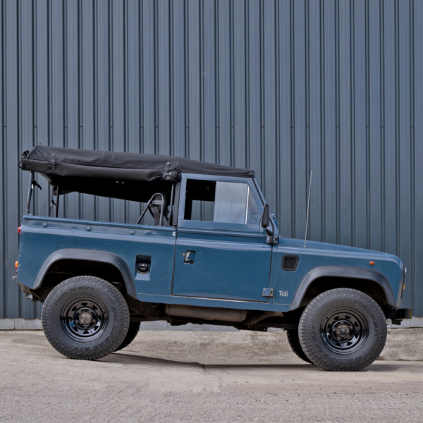 a blue vintage land rover defender sat on tuff torque aftermarket steel wheels